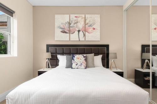 悉尼The Banq Apartments by Urban Rest的卧室配有带鲜花的大型白色床