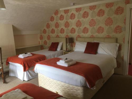 奥斯威斯The New Inn的一间卧室配有两张红色和白色床单