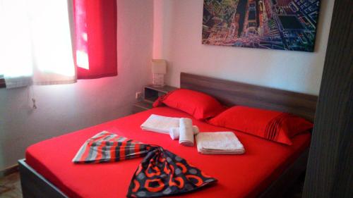 尼坡帝ATHINA'S HOUSE的红色的床,上面有红色的床单和毛巾