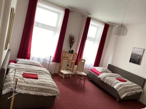 奥洛穆茨奥洛穆茨城市公寓的配有红色窗帘和窗户的客房内的两张床