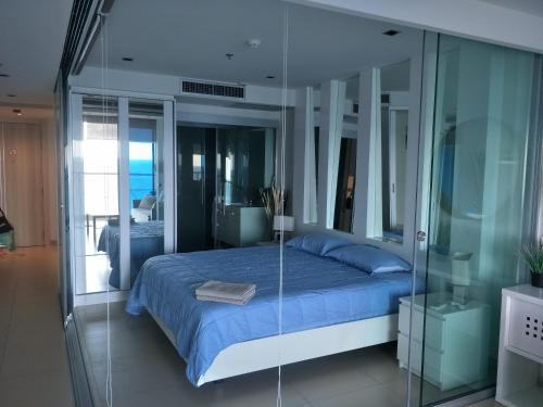 南芭堤雅Sands Pratamnak的一间卧室设有一张床和玻璃墙