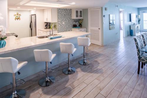 南帕诸岛Saida的厨房铺有木地板,配有白色酒吧凳