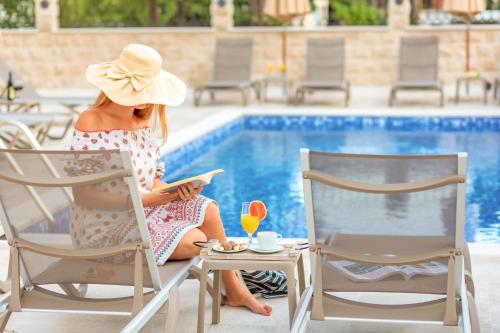 佩特罗瓦纳莫鲁Luxury Apartments Queen的坐在游泳池边椅子上的戴帽子的女人