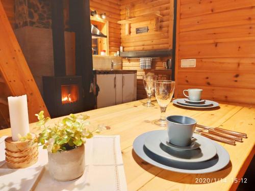Karlsten拉普兰/瑞典溪流小屋的一张带盘子和杯子的木桌和一个壁炉