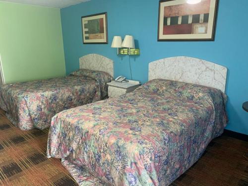 Donalsonville塞米诺尔酒店的两张位于酒店客房的床,拥有蓝色的墙壁