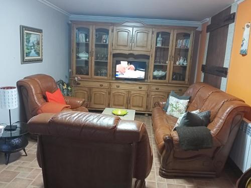 VimianzoCASA O QUINTEIRO的客厅配有2把皮椅和电视