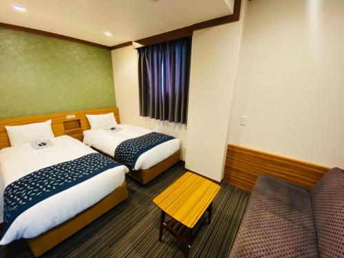 东京上野东金屋酒店的酒店客房,配有两张床和椅子