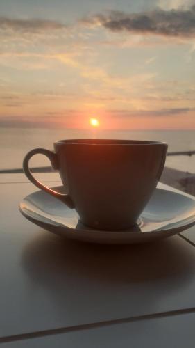 康斯坦察Maritimo Luxury ApartHotel的盘子上的咖啡杯,背景是日落