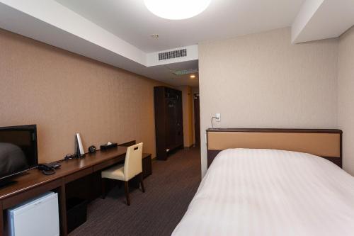 饭田市Silk Hotel的配有一张床和一张书桌的酒店客房