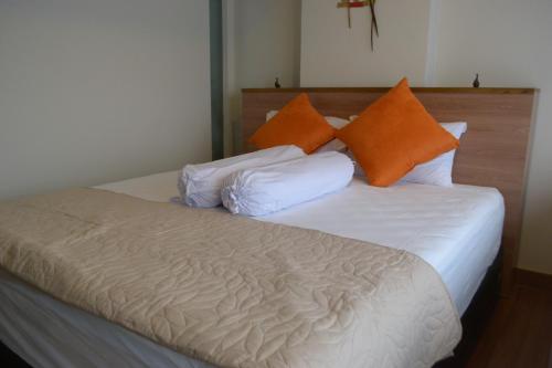 日惹The Cabin Apartment Uttara的一张带橙色和白色枕头的床