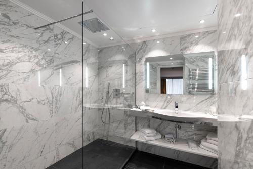 戛纳Juliana Hotel Cannes的一间带水槽和玻璃淋浴的浴室