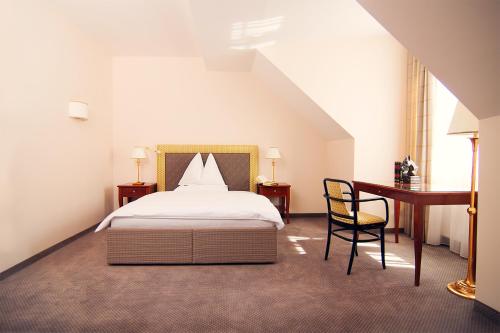 格拉茨Parkhotel Graz - Traditional Luxury的一间卧室配有一张床、一张桌子和一把椅子