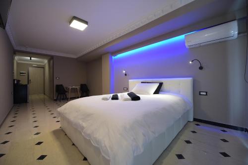 帕特雷Pietra Mare Suites的一间卧室配有一张白色大床,拥有蓝色的灯光