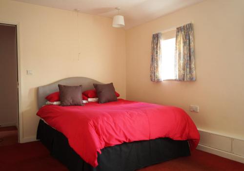 East AnsteyEdge of Exmoor Garden Flat, dog friendly, sleeps 2 - 4的一间卧室配有一张红色的床和窗户