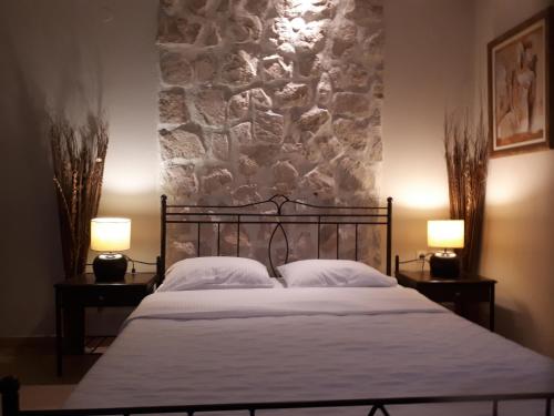 卡斯托里亚戴尔拉戈别墅精品酒店的一间卧室配有一张带两盏灯和石墙的床。