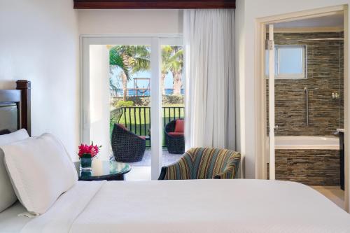 拉纳韦贝Jewel Paradise Cove Adult Beach Resort & Spa的一间卧室配有一张床和一个配有浴缸的阳台