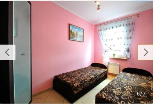 库瑞尼卡慕斯卡APARTAMENT KLAUDIA的卧室设有粉红色的墙壁、一张床和窗户