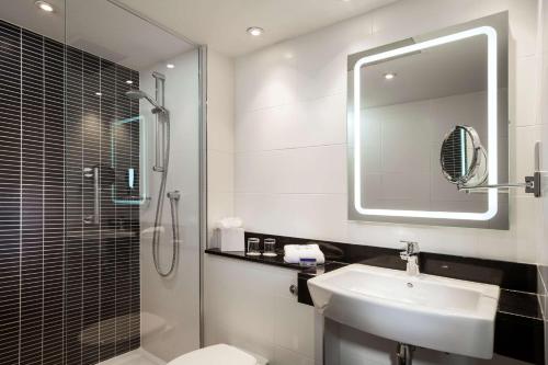 希灵登Radisson Hotel and Conference Centre London Heathrow的一间带水槽、淋浴和镜子的浴室