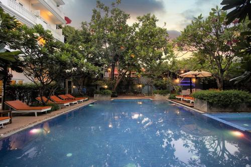暹粒Amber Angkor Villa Hotel & Spa的一座游泳池,位于酒店,设有椅子和树木
