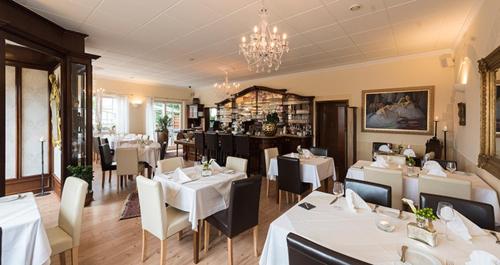 桑德豪森皇家宫廷酒店的餐厅配有白色的桌椅和吊灯