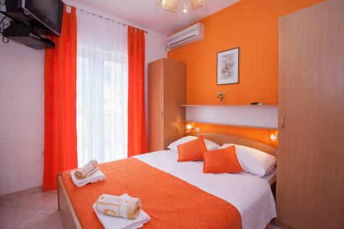 巴斯卡贝林酒店的一间卧室配有一张带橙色墙壁的床和电视。