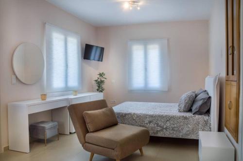 迈萨纳Blanca Serenidad Luxury Apartment的一间卧室配有一张床、一把椅子和镜子