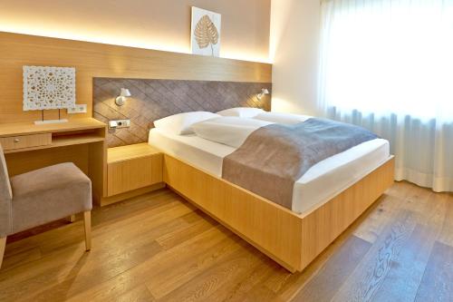 博尔扎诺波斯特葛蕾司酒店的一间卧室配有一张大床和一把椅子
