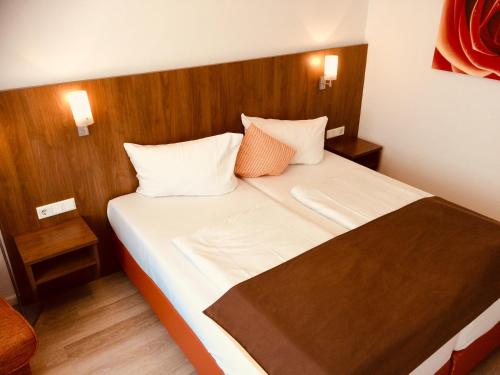 科隆特里顿酒店的一间卧室配有带白色床单和橙色枕头的床。