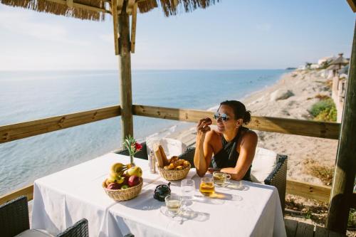 林古泽塔Camping Naturiste Riva Bella 4*的一位妇女在海滩附近的一张桌子上用手机说话