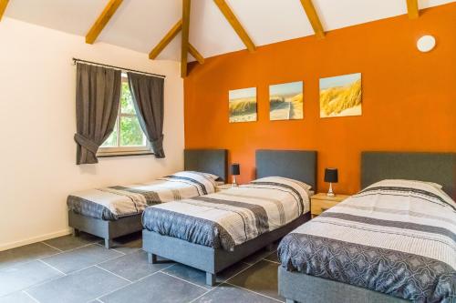 SchimmertValkenhof Schimmert的橙色墙壁的客房内的三张床