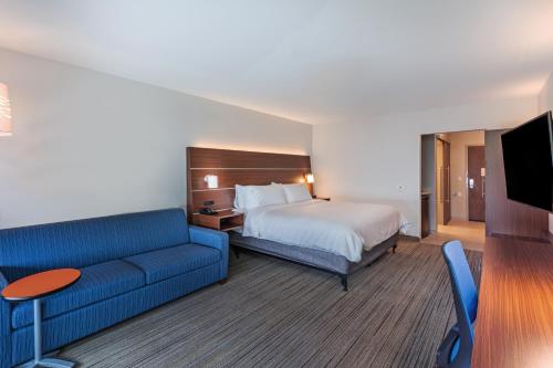ParsonsHoliday Inn Express & Suites - Parsons, an IHG Hotel的酒店客房,配有床和蓝色的沙发