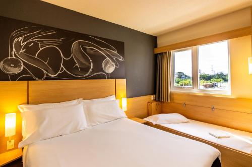 阿雷格里港Ibis Porto Alegre Assis Brasil的酒店客房设有两张床和窗户。