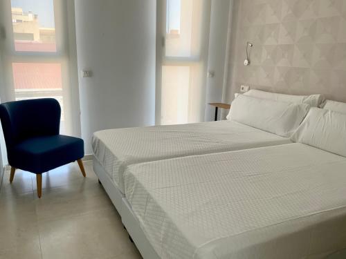 塞维利亚Apartamentos Rivero 8的一间卧室配有一张床和一张蓝色椅子