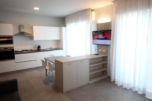 阿尔玛·迪·塔吉亚Persea mare appartamenti的厨房配有白色橱柜和桌椅