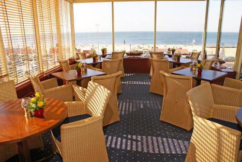 斯海弗宁恩席凡宁根林荫酒店的一间带桌椅的餐厅,享有海滩美景