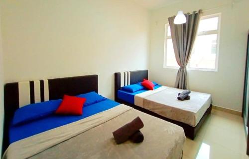 新山Sri Penawar Harmoni Sweet Grace X Desaru Coast Water Park Johor Bahru的一间卧室配有两张带蓝色和红色枕头的床