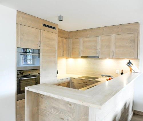 格里门茨Luxury Grimentz Apartment的厨房配有木制橱柜和白色台面