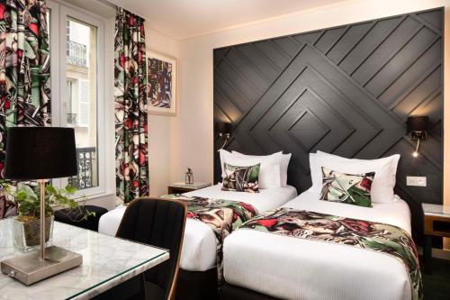 巴黎蒙马特艺术酒店的酒店客房设有两张床和一张桌子。
