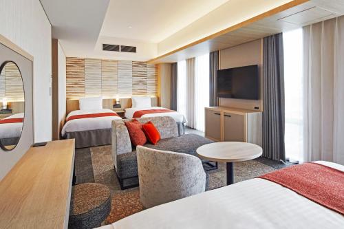 京都Hotel Emion Kyoto的酒店客房设有两张床和电视。