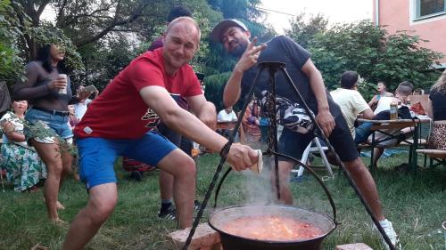 布达佩斯Budapest Garden Hostel的两个男人在院子里的烤架上做饭