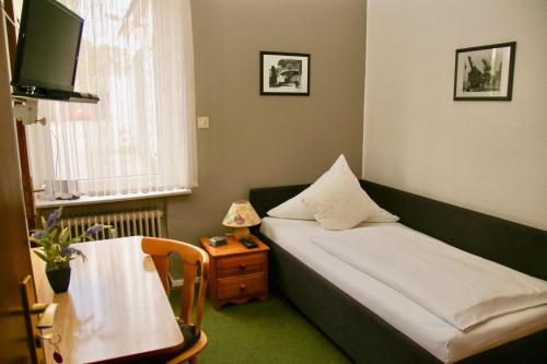 汉堡Hotel Meiendorfer Park的小房间设有一张床和一张带台灯的桌子