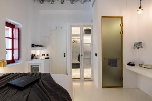 米克诺斯城The TownHouse Mykonos的一间卧室配有一张床,一扇门通往浴室