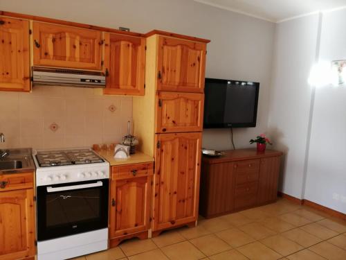 安杰拉La maison de Lidia的一间带木制橱柜和炉灶的厨房以及一台电视。