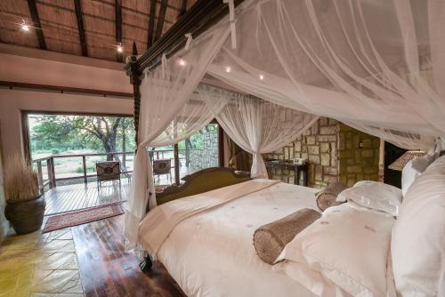 荆棘丛自然保护区Shumbalala Game Lodge的一间卧室配有一张带天蓬的床