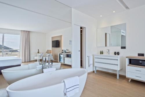 锡切斯锡切斯美利亚酒店的白色的客厅配有白色的沙发和浴缸。