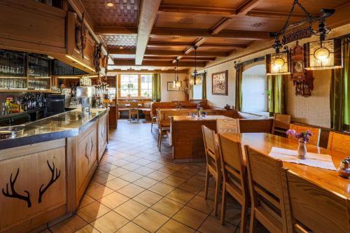 KollnburgBurggasthof Hauptmann的一间带木桌椅的餐厅和一间酒吧
