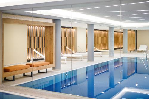 慕尼黑慕尼黑诺沃特酒店的大楼内一个带桌椅的游泳池