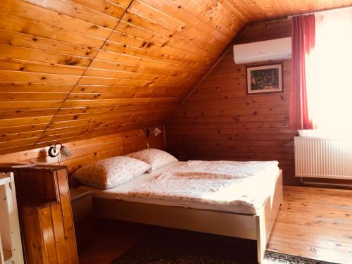 巴拉通雷勒Lellei Pihenőház Balatonlelle的木制客房内的一间卧室,配有一张床