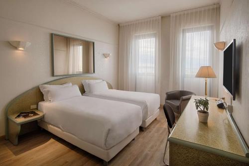 安科纳NH安科纳酒店的酒店客房设有一张白色大床和一张书桌