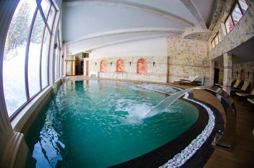 潘波洛沃卡梅利亚大厦酒店的一座带瀑布的游泳池,位于一座带窗户的建筑中